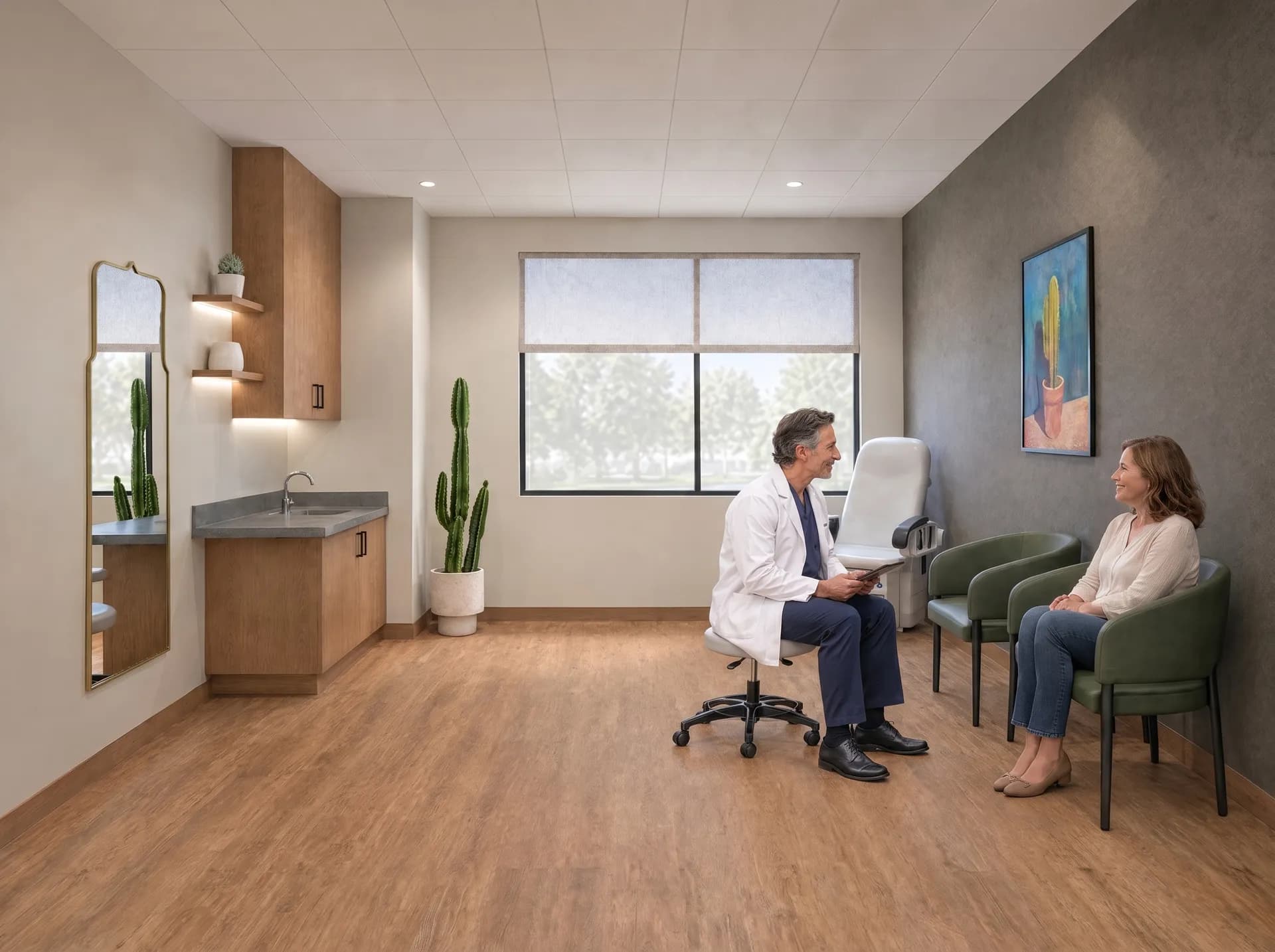 A surgeon on a rolling stool talking with a patient seated in a green armchair in a treatment suite at Alta Medical